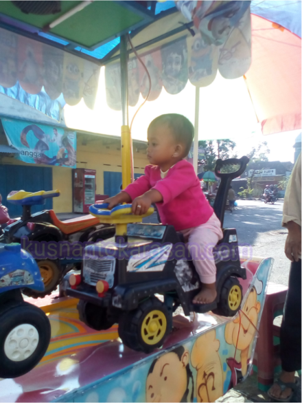 Seorang anak batita sedang naik odong-odong